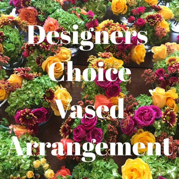 Assorted small floral arrangements with roses and mums on a table