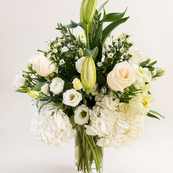 White roses and lilies arranged in a clear glass vase