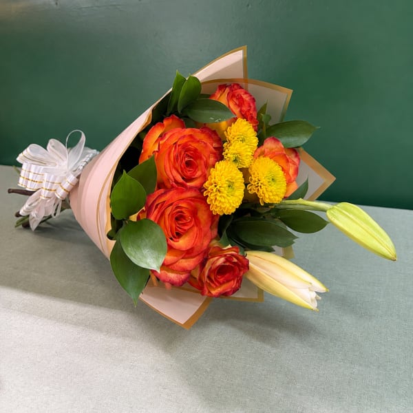 Bouquet of orange roses and yellow mums wrapped in pink paper