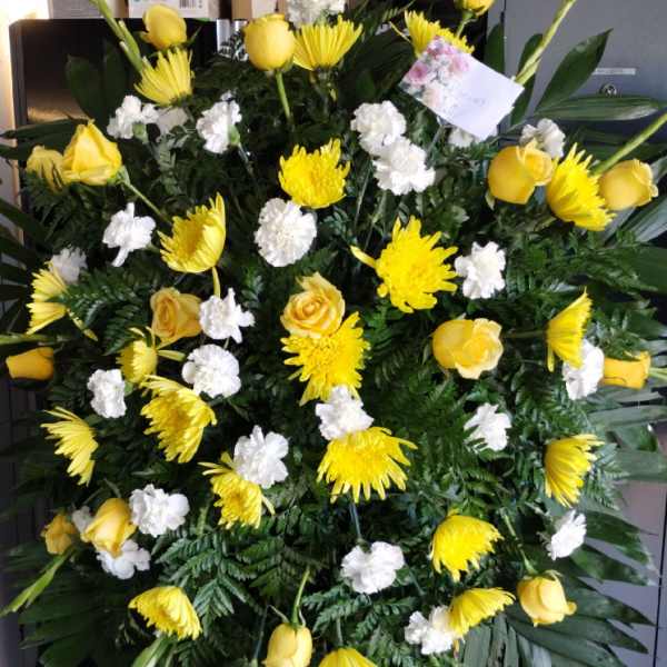 Large standing spray with yellow roses, yellow mums, and white carnations on an easel