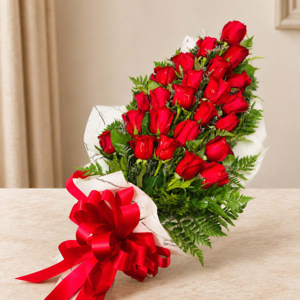 Bouquet of red roses wrapped in white paper with a red ribbon