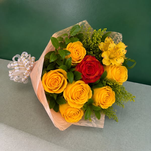 Bouquet of yellow and red roses with yellow alstroemeria in pink wrap