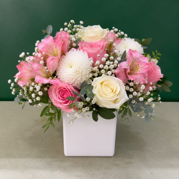 Pink and white flower arrangement in a white square vase