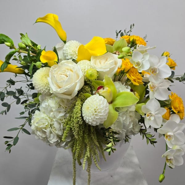 White and yellow floral arrangement in a white vase