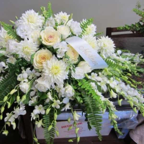 White floral casket spray with cream roses and daisies