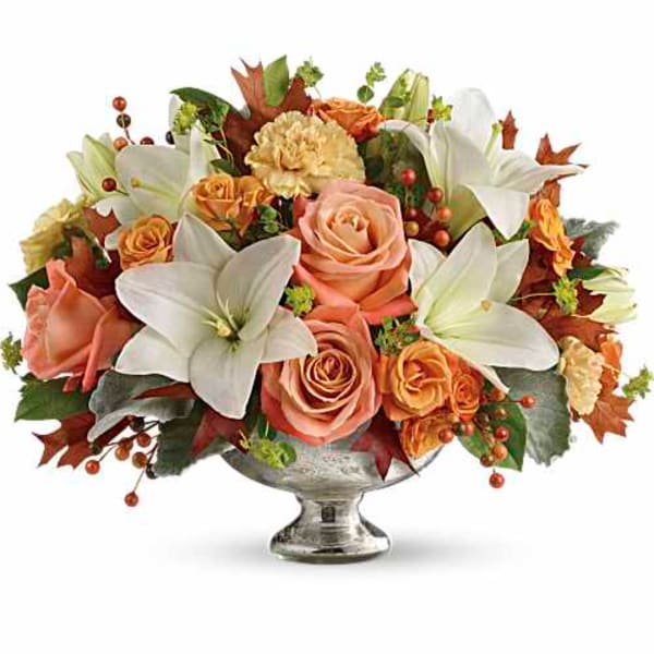 Peach roses and white lilies in a silver pedestal vase