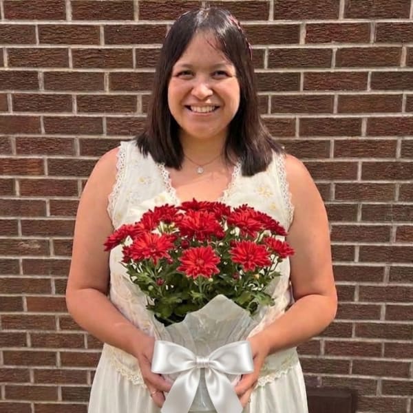 Woman holding a bouquet of red flowers wrapped in white paper