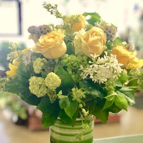 Yellow roses and white filler flowers in a glass vase