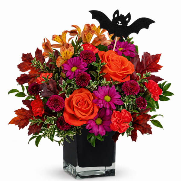Orange and magenta flowers in a black vase with a bat pick