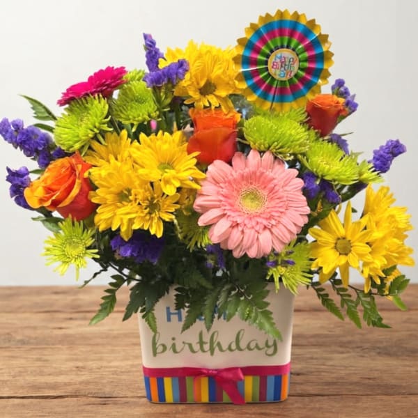 Colorful birthday flower arrangement in a decorated square container