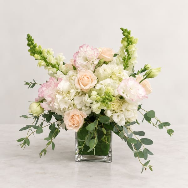 Wedding bouquet in a square glass vase with blush roses and white blooms