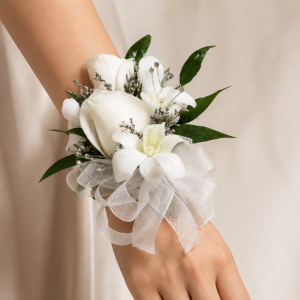 White floral wrist corsage with ribbon and green leaves