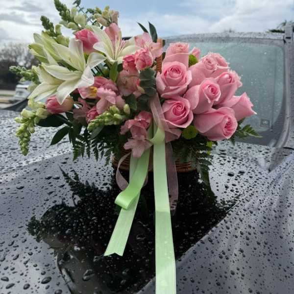 Pink rose and lily bouquet with ribbon on a car hood