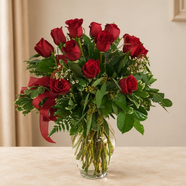Red roses arranged in a clear glass vase with a red ribbon