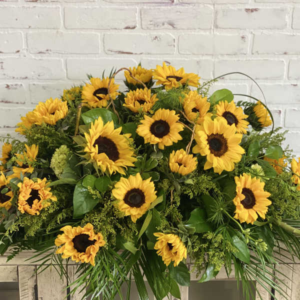 Large sunflower arrangement with greenery on a wooden table