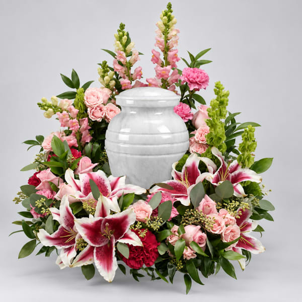 Pink and white floral arrangement surrounding a white urn