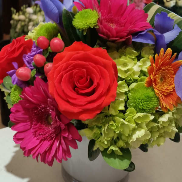 Colorful mixed bouquet in a white vase with red roses and bright gerbera daisies