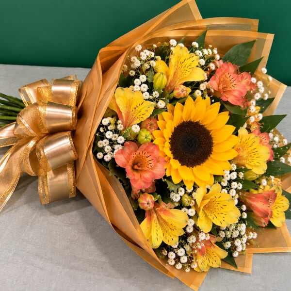 Bouquet of sunflowers and orange alstroemeria wrapped in gold paper
