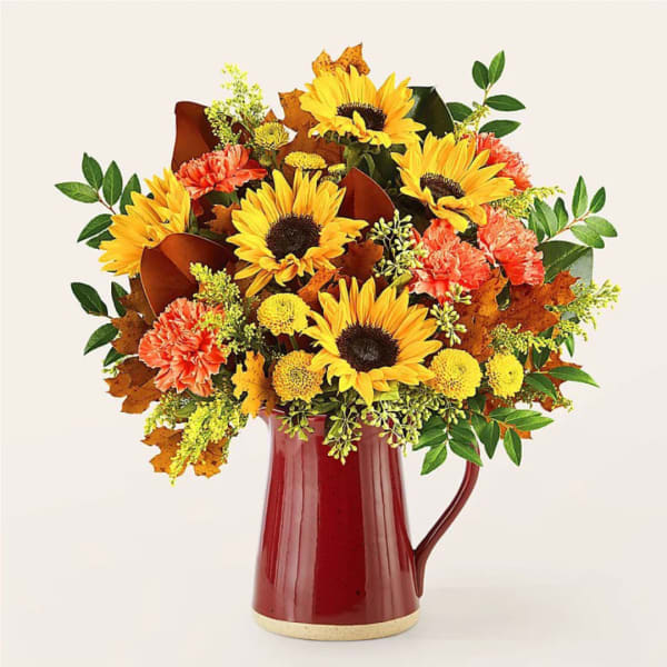 Sunflower and carnation arrangement in a red pitcher vase