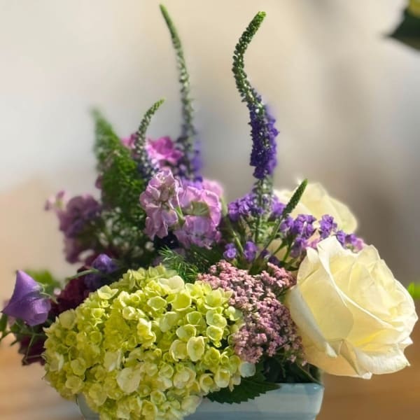 Mixed bouquet with pale yellow roses, green hydrangea, and purple flowers