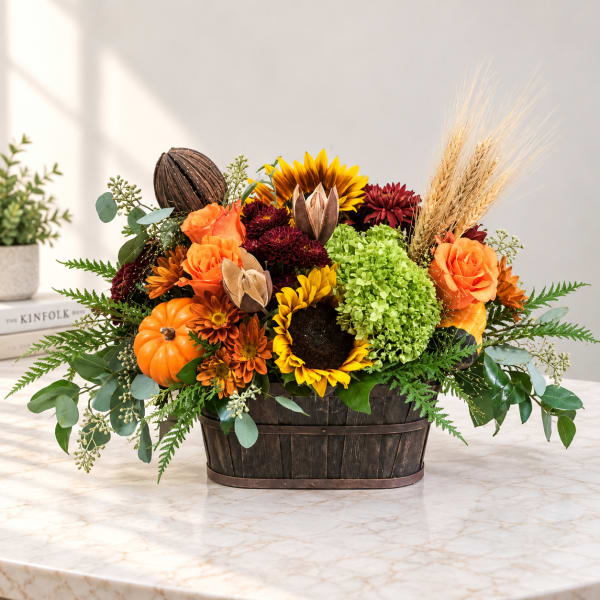 Autumn floral arrangement with sunflowers, roses, mums, and pumpkins in a wooden basket