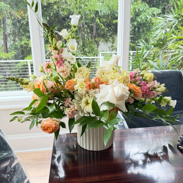 Mixed pastel flower arrangement in a white ribbed vase on a table
