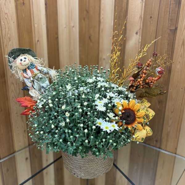 Fall floral arrangement in a woven basket with a scarecrow decoration
