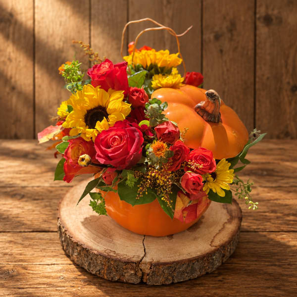 Pumpkin-shaped floral arrangement with red roses and yellow sunflowers