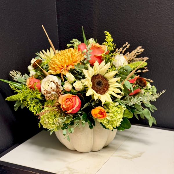 Mixed bouquet in a white pumpkin-shaped vase with sunflowers and roses
