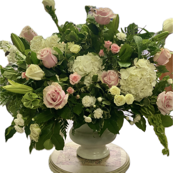 Pink and white roses with hydrangeas in a white urn vase