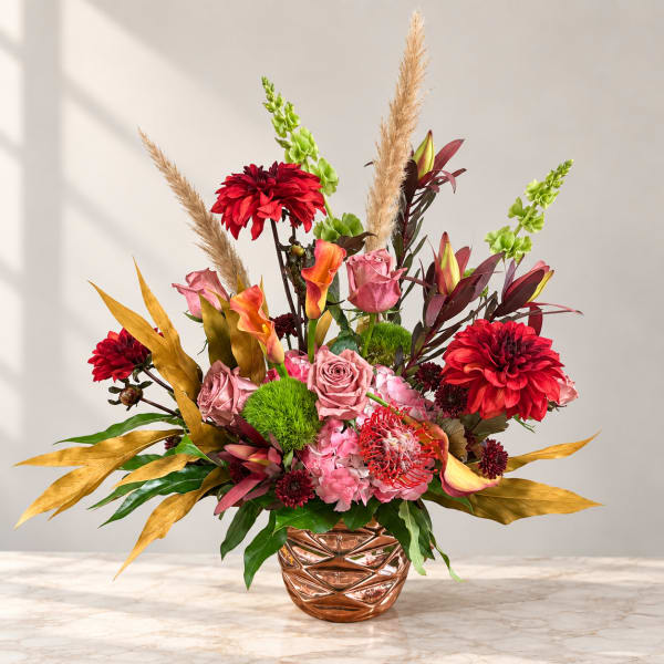 Mixed floral arrangement in a copper vase with red, pink, and orange blooms