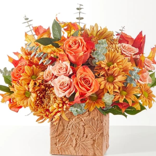 Autumn bouquet of orange roses and yellow daisies in a carved vase
