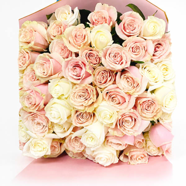 Bouquet of pale pink and cream roses wrapped in pink paper