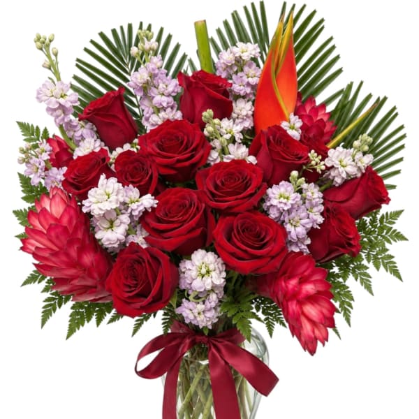Bouquet of red roses and tropical flowers in a glass vase with a ribbon