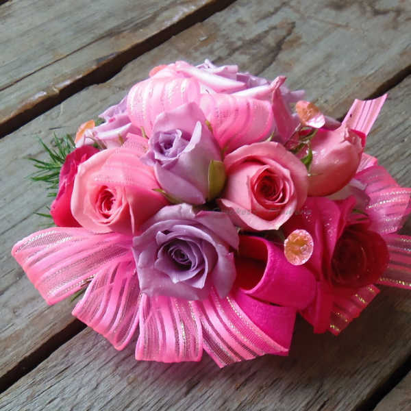 Pink and lavender rose bouquet with ribbon accents on a wooden surface