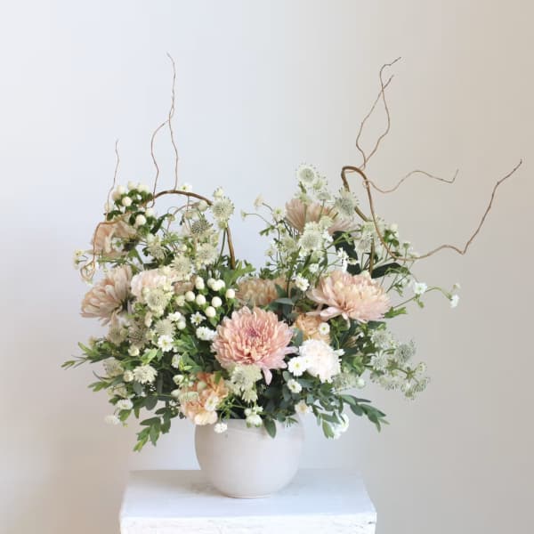 Blush and white floral arrangement in a white vase with curly branches
