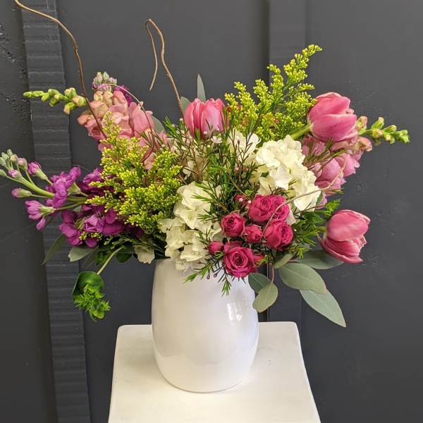Mixed pink and white floral arrangement in a white vase