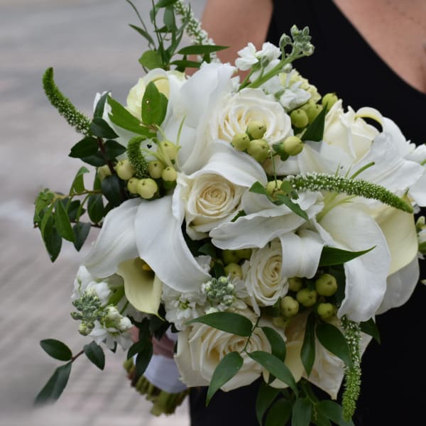 White rose and calla lily bouquet with green berries and foliage