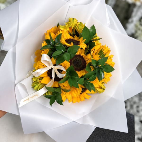 Bouquet of yellow sunflowers wrapped in white paper with a ribbon