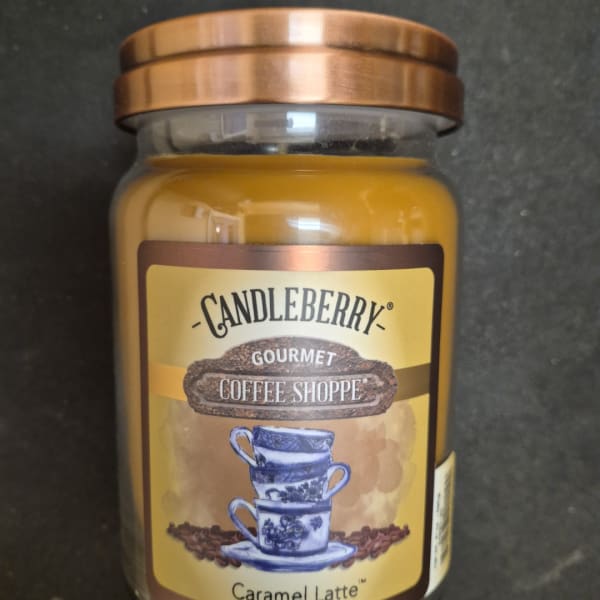 A caramel latte scented candle in a glass jar with a copper lid