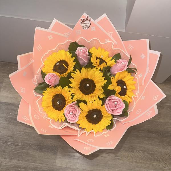 Bouquet of yellow sunflowers and pink roses wrapped in pink paper