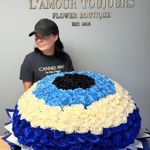 Large round bouquet of blue, white, and black roses held by a woman