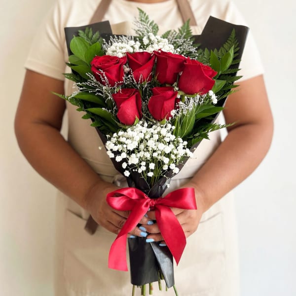 Bouquet of red roses with white baby's breath wrapped in black paper and tied with a red ribbon