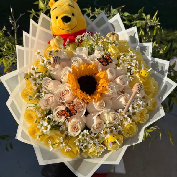 Bouquet of yellow and cream roses with a sunflower and a Winnie the Pooh plush