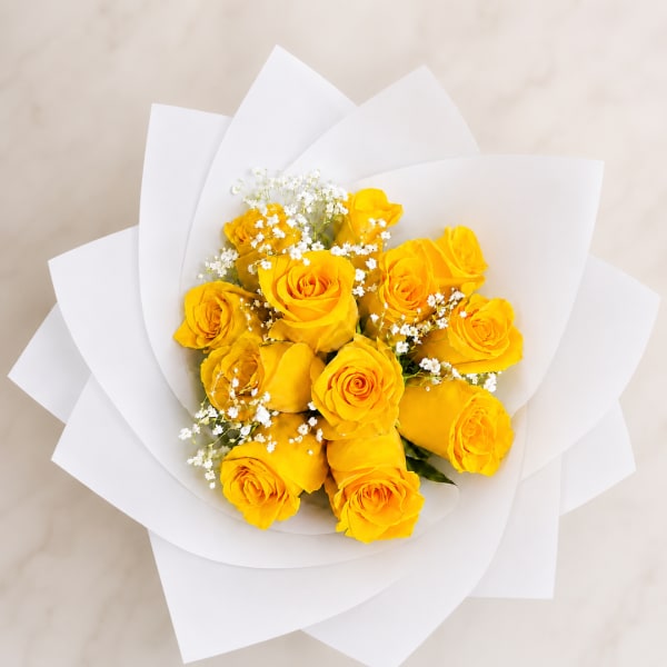 Bouquet of yellow roses with white filler flowers in white paper wrap