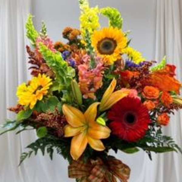 Colorful mixed bouquet with sunflowers, lilies, and gerbera daisies in a glass vase