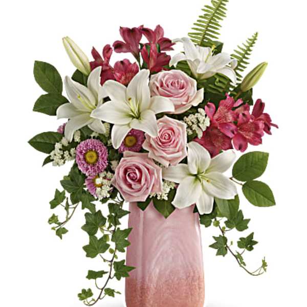 Pink roses and white lilies in a pink vase with trailing ivy