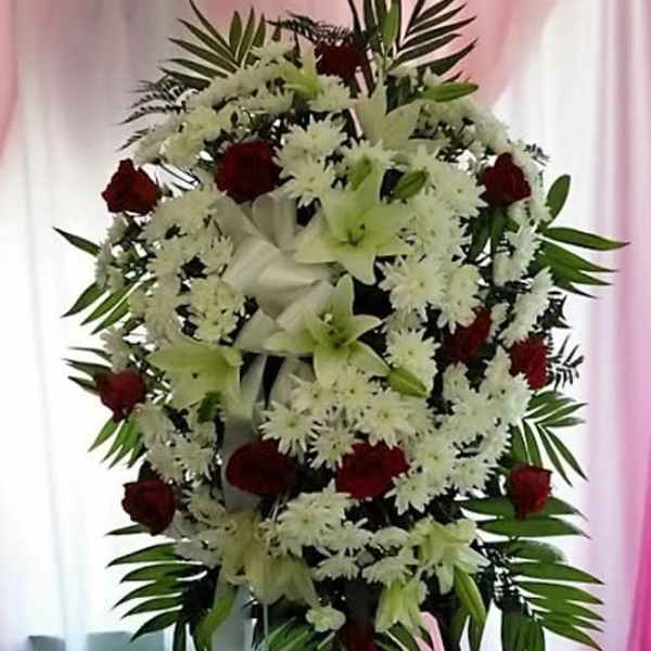 Standing floral spray with white lilies, white daisies, and red roses
