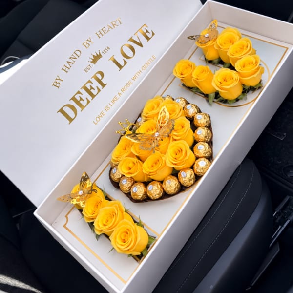 Yellow roses arranged in a gift box with chocolates and butterfly decorations