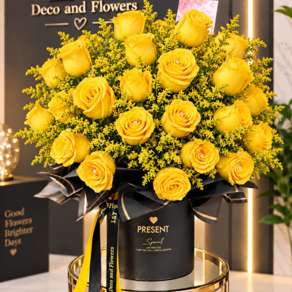 Yellow roses arranged in a black gift box with ribbon.